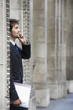 Businessman standing by colonnade pillars talking on cell phone