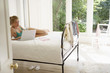 Young woman reclining on bed using laptop