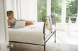 Young woman reclining on bed using laptop