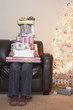Person holding stack of Christmas gifts on sofa