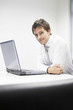 Contented Businessman sitting at desk with Laptop, portrait