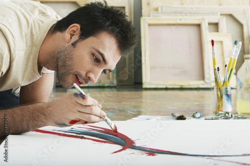 Photo: Man painting on canvas, on studio floor Man painting on canvas, on studio floor