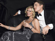 Couple in back of car drinking champagne, looking away