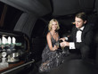Couple in back of limousine drinking champagne
