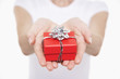 Woman offering small gift, mid section, close-up on hands