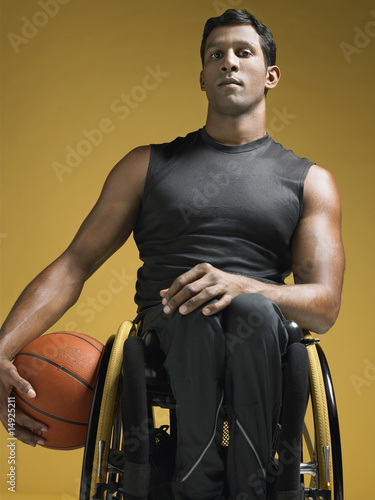 Photo: Paraplegic athlete sitting in wheelchair holding basketball Paraplegic athlete sitting in wheelchair holding basketball