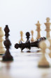 Chess game, king lying on board surrounded by pieces
