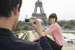 Couple Using Camera Phone and Eiffel Tower