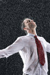 Businessman standing, arms spread facing incoming rain
