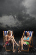 Sunbathers sitting in sunloungers during downpour