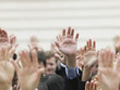 Crowd of people raising hands, focus on hands