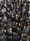 Photo: Large group of business people clapping, surrounding woman looking up, elevated view Large group of business people clapping, surrounding woman looking up, elevated view