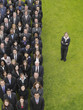 Photo: Business woman standing next to large group of business people in formation, elevated view, portrait Business woman standing next to large group of business people in formation, elevated view, portrait