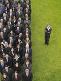 Photo: Business woman standing next to large group of business people in formation, elevated view, portrait Business woman standing next to large group of business people in formation, elevated view, portrait