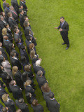 Photo: Business man facing large group of business people in formation, elevated view Business man facing large group of business people in formation, elevated view