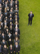 Photo: Business man standing next to large group of business people in formation, elevated view, portrait Business man standing next to large group of business people in formation, elevated view, portrait