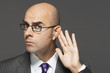 Balding man with hand behind ear, listening closely
