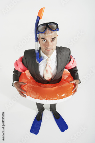 Photo: Middle-aged businessman in flippers, inflatable rubber ring, snorkel and goggles Middle-aged businessman in flippers, inflatable rubber ring, snorkel and goggles