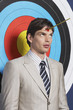 Man with toy arrow on forehead, standing in front of target