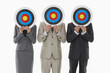 Photo: Three business people holding targets in front of faces against white background Three business people holding targets in front of faces against white background