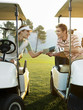 Young golfers sitting in golf cart, holding score card
