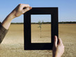 Woman framing tree in desert, close-up of hands and frame
