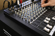 Man adjusting knob on mixing console, close-up.
