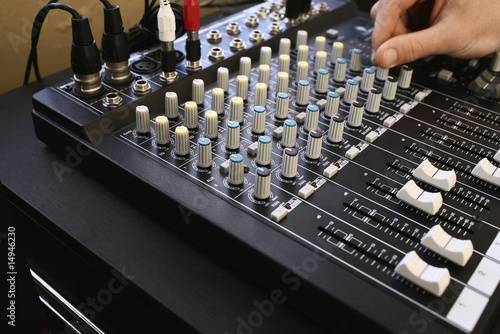 Photo: Man adjusting knob on mixing console, close-up. Man adjusting knob on mixing console, close-up.