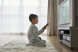 Boy 7-9 sitting on floor, watching cartoons in television