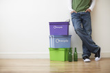 Photo: Low section view of young man leaning against wall next to small pile of recyling containers Low section view of young man leaning against wall next to small pile of recyling containers
