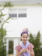 Foto: Girl 10-12 in tiara and feather boa standing outside house Girl 10-12 in tiara and feather boa standing outside house