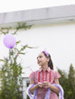 Foto: Girl 10-12 in feather boa holding balloon outside house Girl 10-12 in feather boa holding balloon outside house