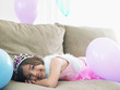 Foto: Young girl 7-9 lying on sofa with balloons, smiling Young girl 7-9 lying on sofa with balloons, smiling