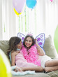 Foto: Portrait of two girls 7-9, 10-12 sitting on sofa in party costumes Portrait of two girls 7-9, 10-12 sitting on sofa in party costumes
