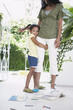 Girl 5-6 years hugging mothers leg, standing on verandah