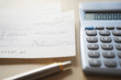 Calculator, pen and filled cheque on table, close-up