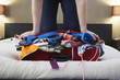 Woman kneeling on overstuffed suitcase, low section