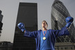 Foto: Boxer wearing gold medal standing in front of downtown skyscrapers, low angle view, London, England Boxer wearing gold medal standing in front of downtown skyscrapers, low angle view, London, England