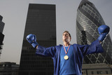 Photo: Boxer wearing gold medal standing in front of downtown skyscrapers, low angle view, London, England Boxer wearing gold medal standing in front of downtown skyscrapers, low angle view, London, England