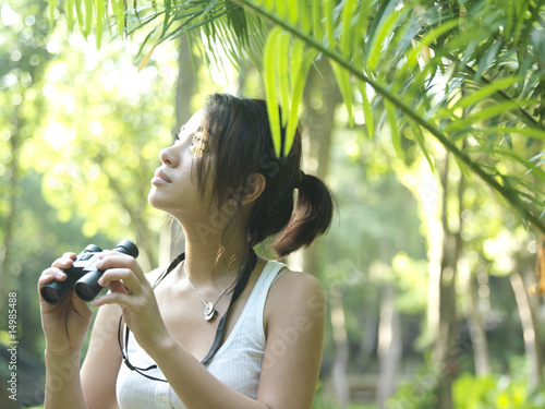 Foto: Young woman in tropical forest, holding binoculars Young woman in tropical forest, holding binoculars