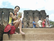 Photo: Young woman sitting on steps, talking on mobile phone, holding guide book Young woman sitting on steps, talking on mobile phone, holding guide book