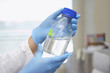 Chemist holding bottle of solution in laboratory, close-up of hands