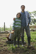Father standing with arm round son 7-9 in sty with pig, portrait