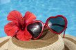 Gafas de sol y sombrero al lado de una piscina azul Gafas de sol y sombrero al lado de una piscina azul