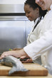 Two chefs preparing salmon in kitchen