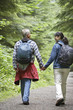 Couple walking along forest road, rear view