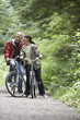 Senior man and middle-aged woman on bicycles in forest, laughing