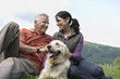Couple and golden retriever resting on grass