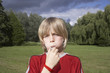 Portrait of boy 7-9 blowing whistle in meadow