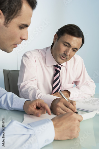 Photo: Two business men working at table in office Two business men working at table in office